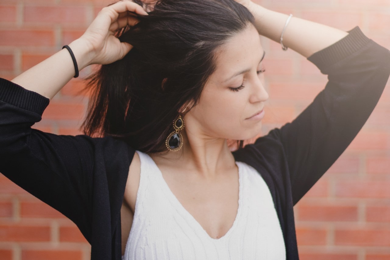 A woman wearing spinel drop earrings stretches outside.