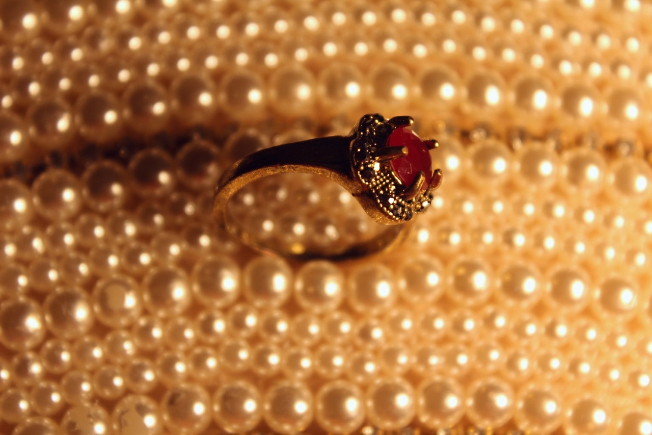 A yellow gold spinel fashion ring sits among pearls.