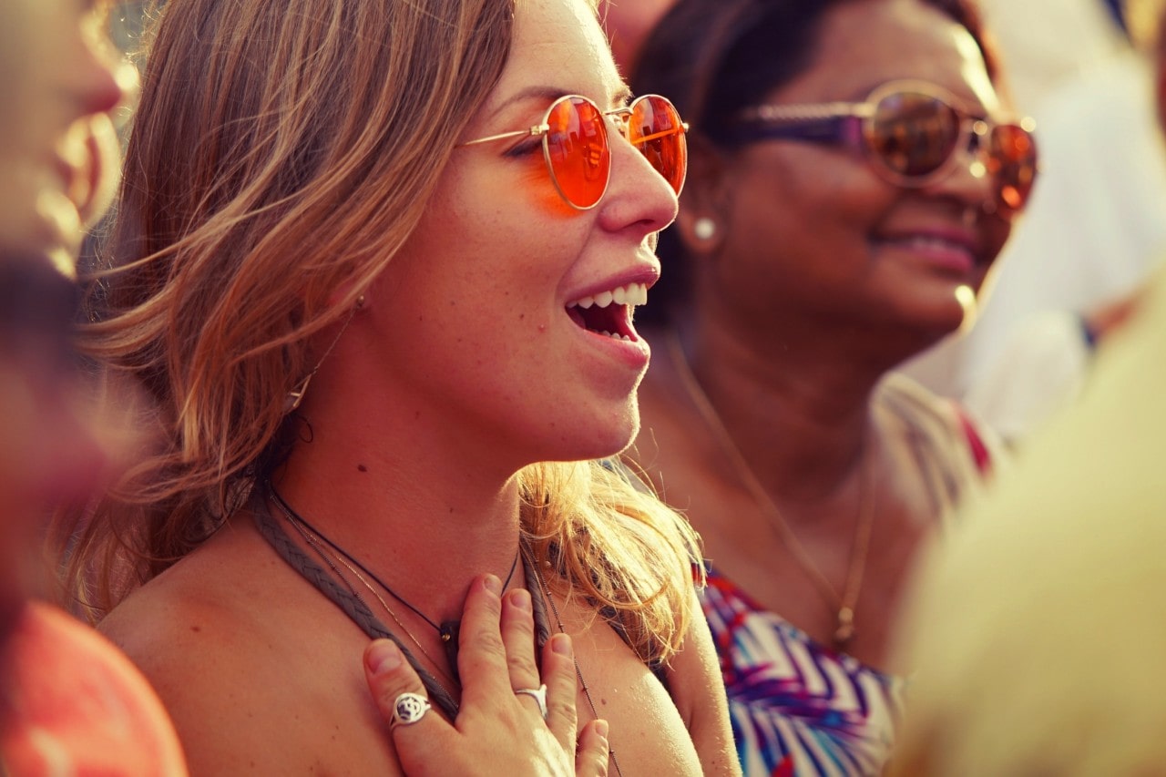 Women wearing sunglasses and fashion jewellery, enjoying a lively outdoor event.