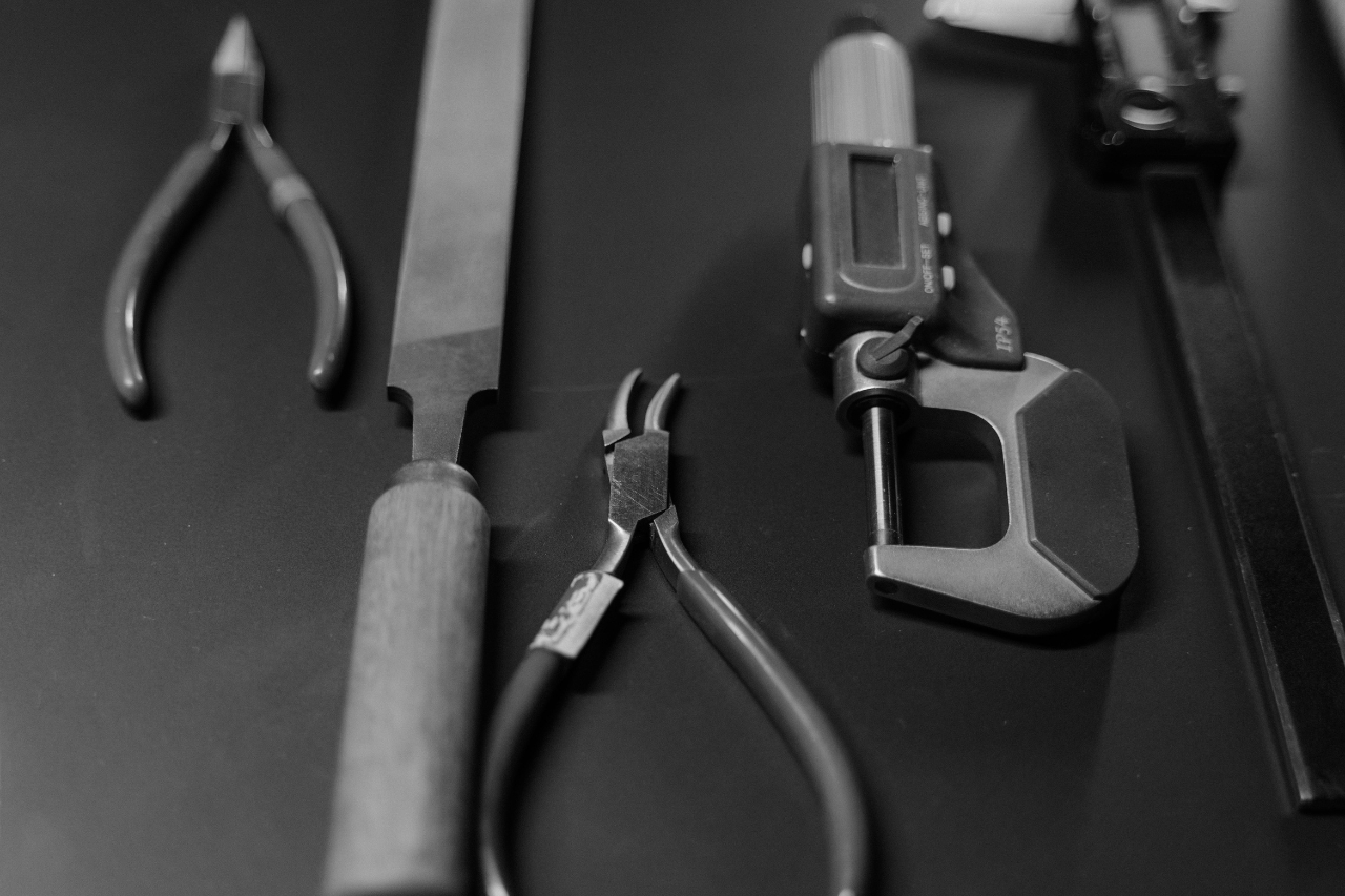 A black and white close-up of jeweller’s tools on a mat.