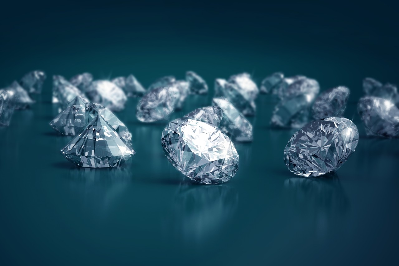 A selection of sparkling round cut diamonds on a dark teal background.