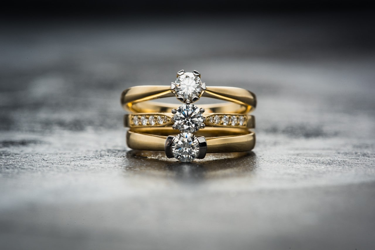 three yellow gold and diamond engagement rings stacked up