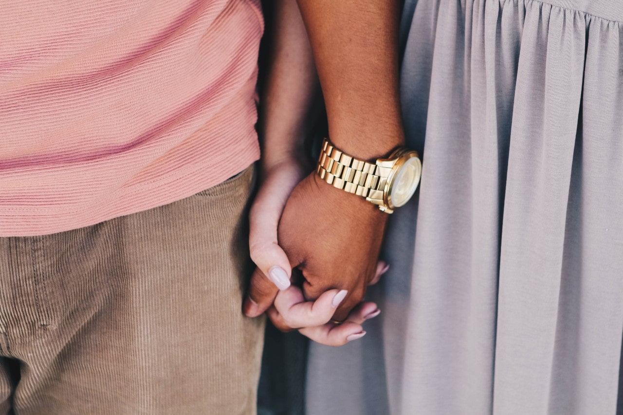 a couple holding hands, the man wearing a yellow gold luxury timepiece