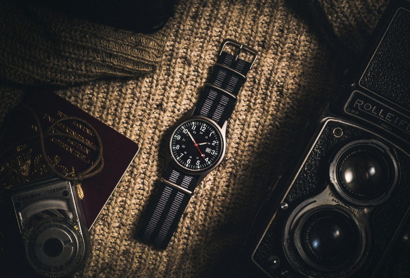 a black watch sitting next to a camera and various travel items