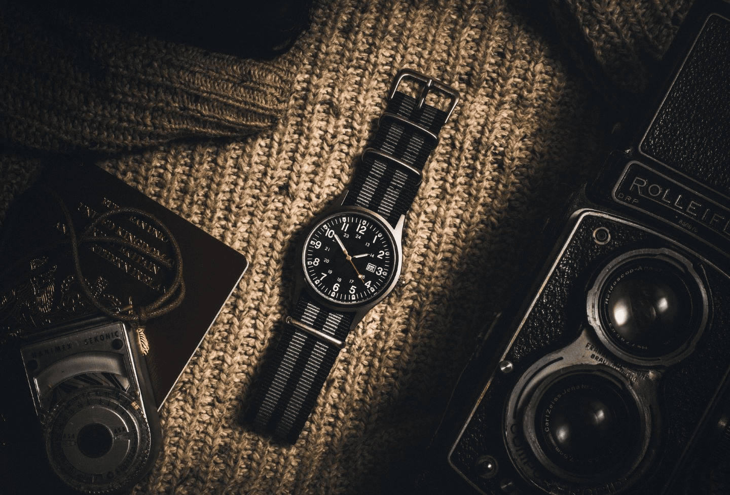 a black watch sitting next to a camera and various travel items