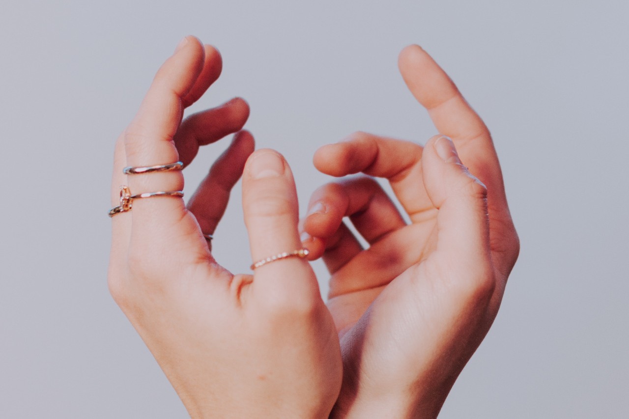 a pair of hands reaching upwards and wearing a number of thin rose gold fashion rings