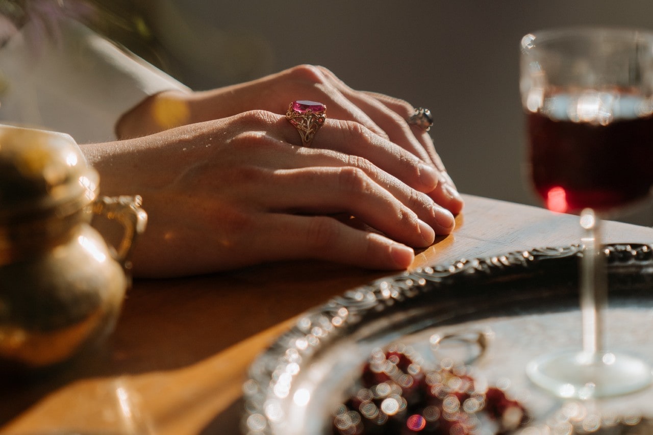 a pair of hands on a table wearing two gemstone rings