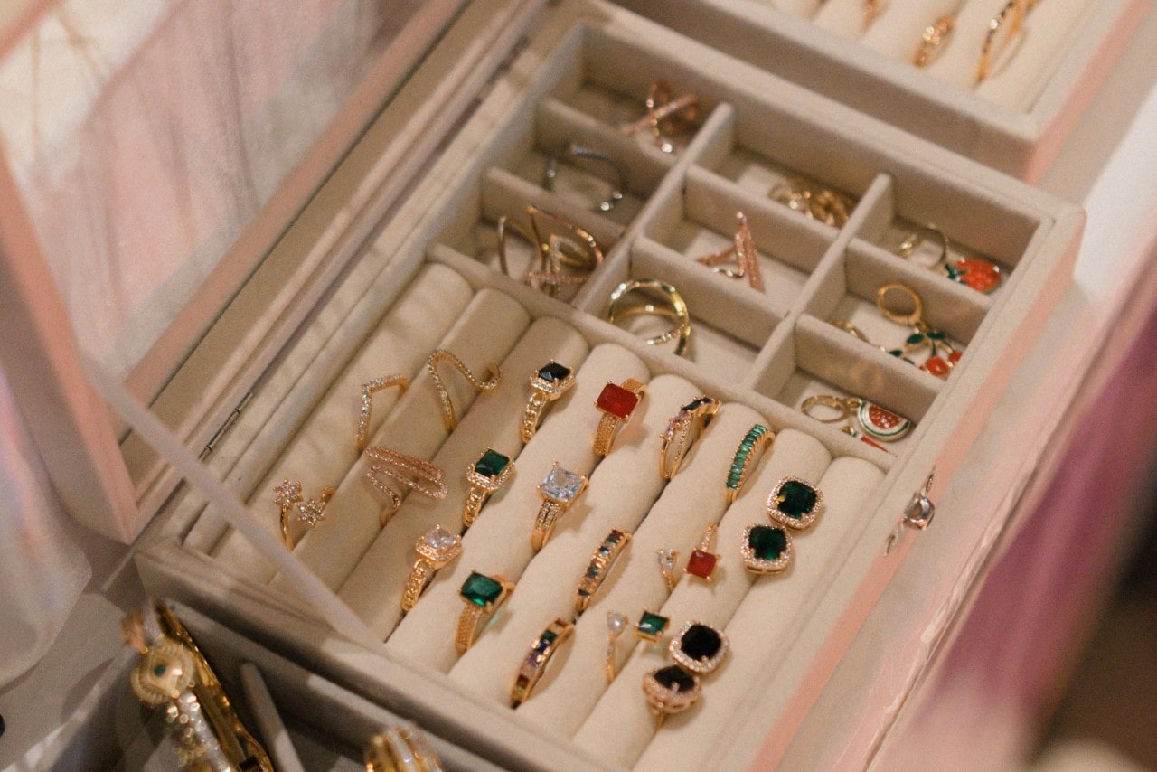 An organized jewelry box displays an assortment of gold rings with colorful gemstones and intricate designs. An organized jewelry box displays an assortment of gold rings with colorful gemstones and intricate designs.
