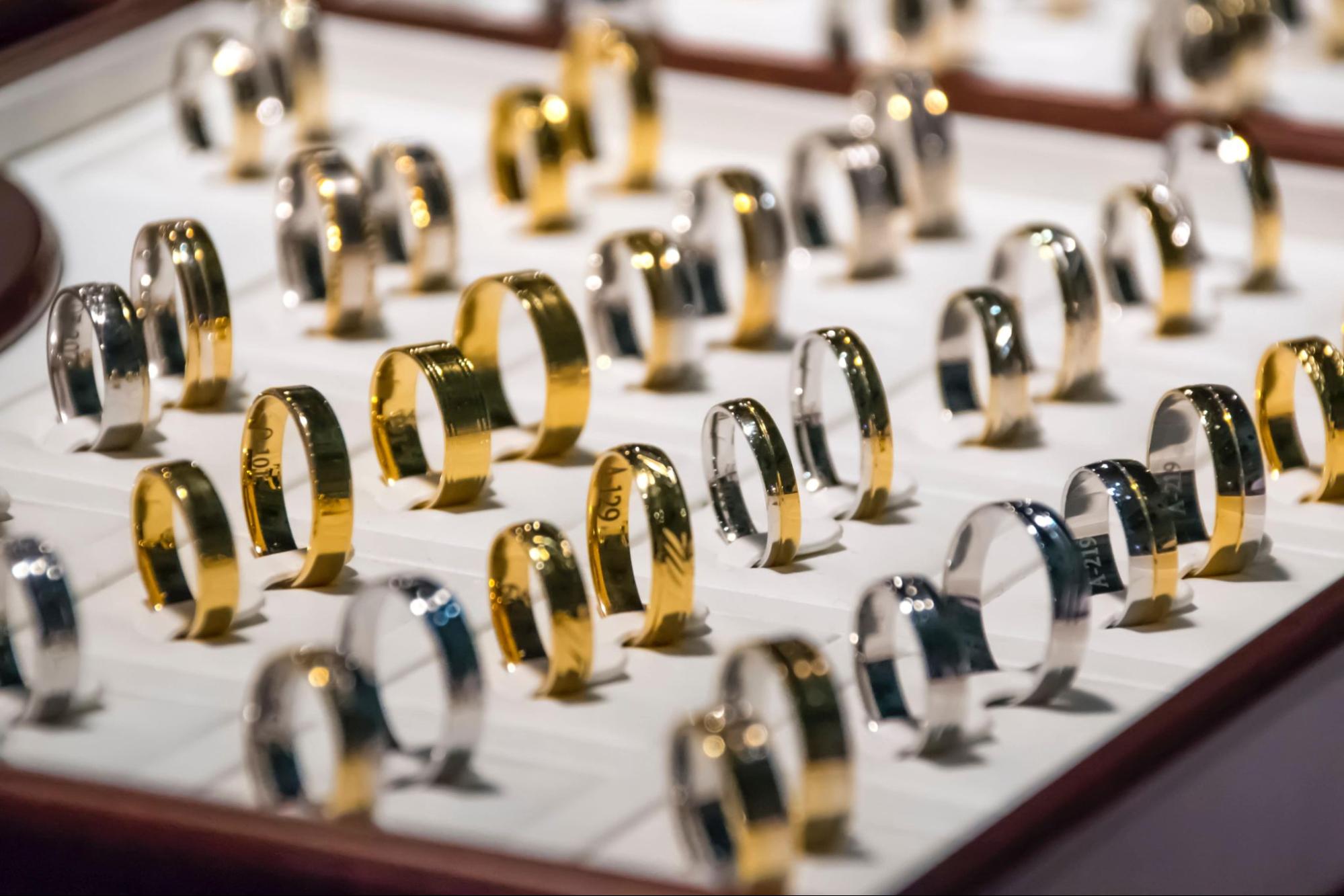 A close up of yellow and white gold wedding bands held upright on a display.
