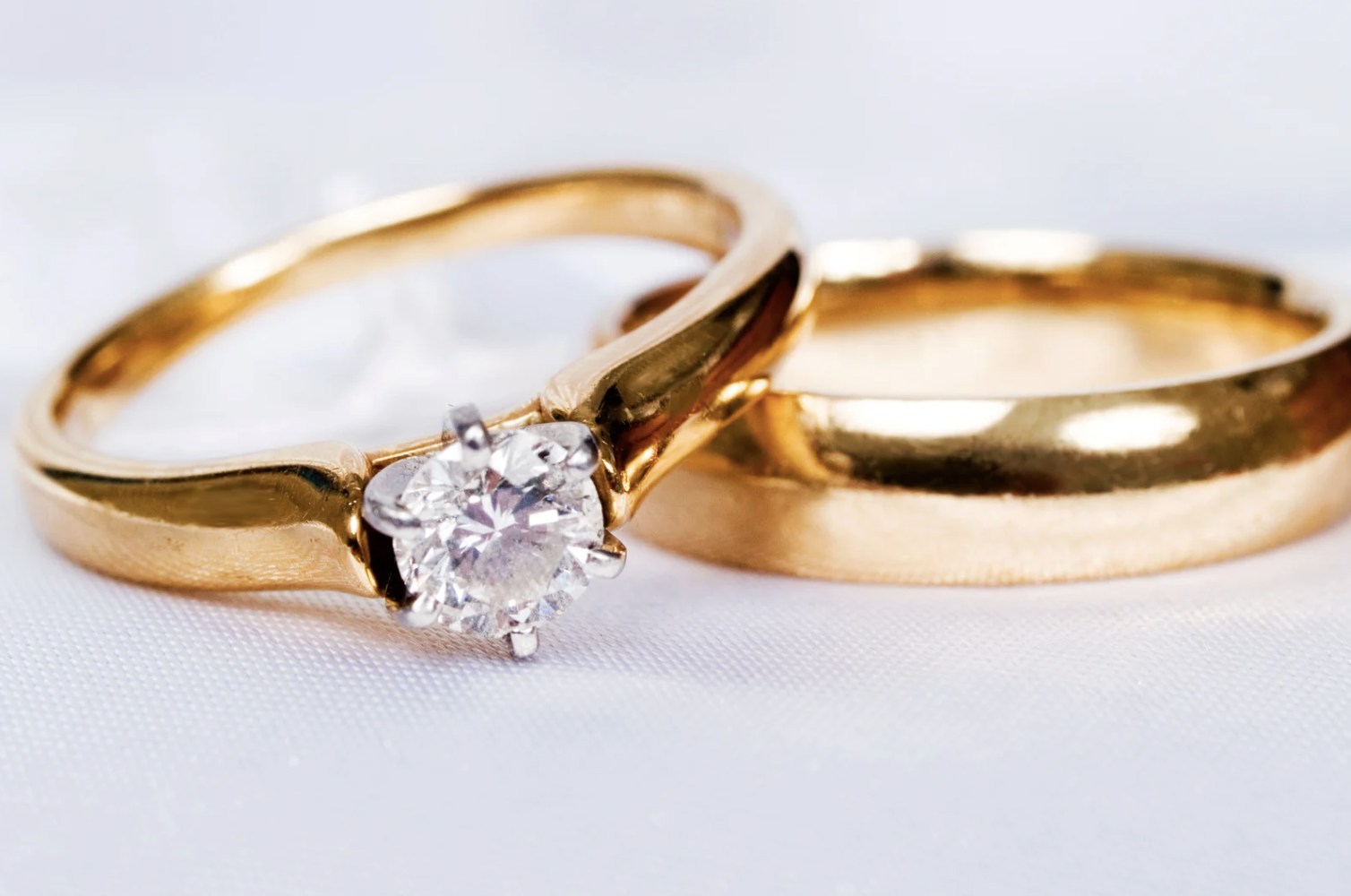 Two yellow gold wedding bands, one with a diamond and one polished.